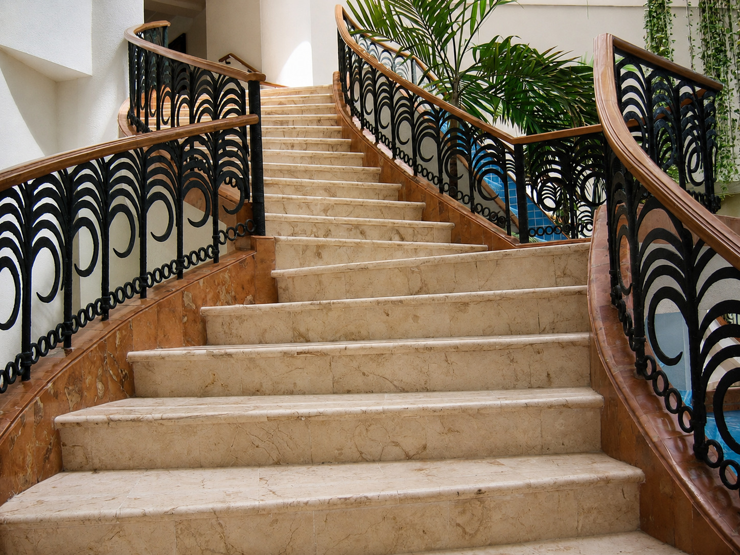 Escalera doble en mármol Crema Marfil con barandal de herrería y madera